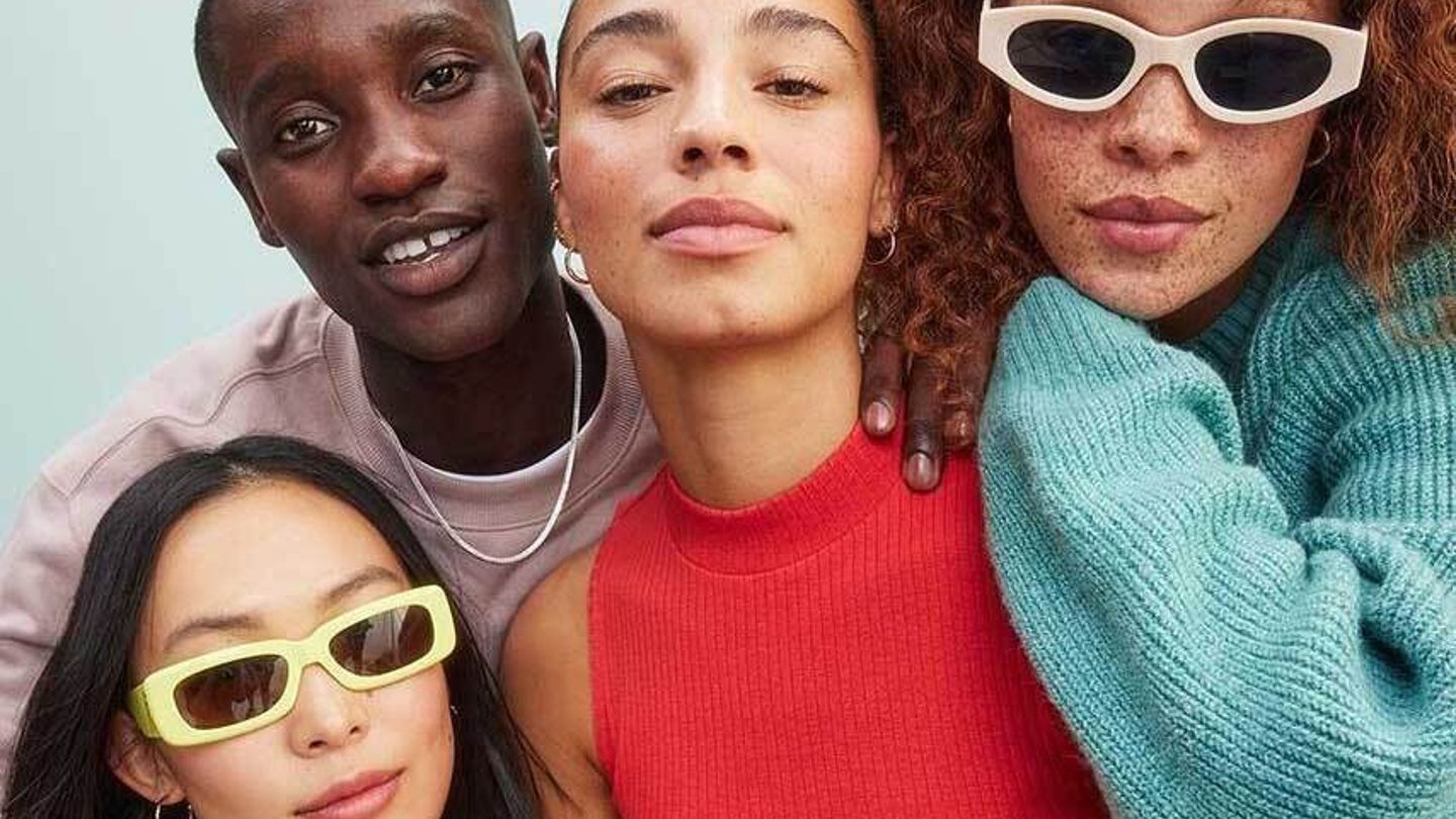 Stylish group of diverse friends posing confidently in colorful outfits and trendy sunglasses