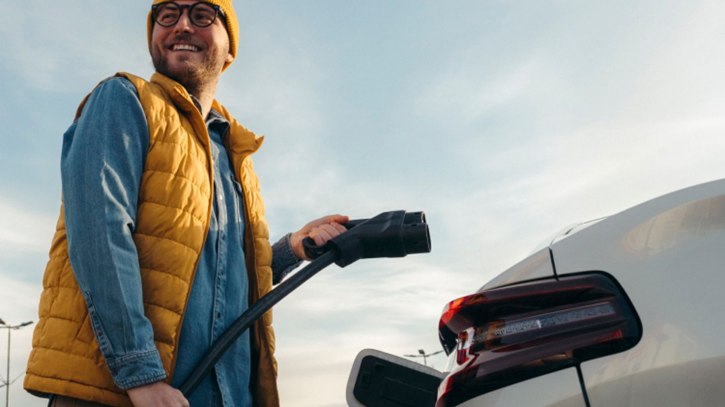 Image shows a man getting ready to charge his car. Audi, and PHD logos are featured at the top left corner of the image.