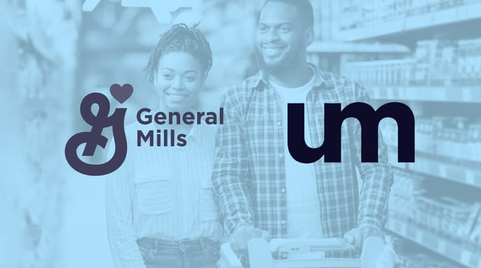 Smiling adult couple shopping together in a grocery store aisle, pushing a cart filled with items.