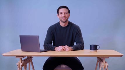 Man sitting at a desk and smiling, still from a Resource Desk video