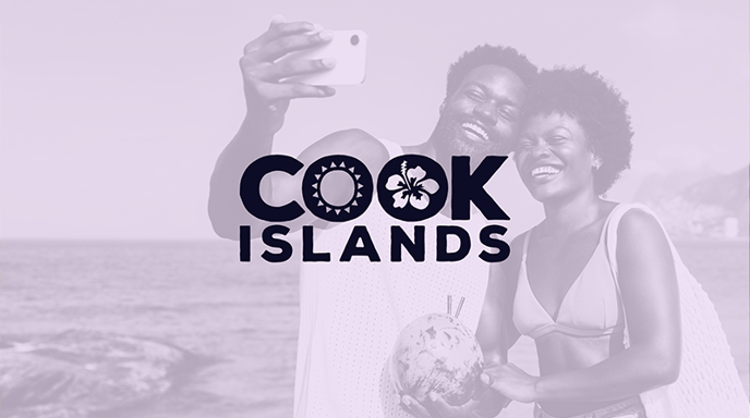 A promotional image with a soft-toned filter, featuring the Cook Islands logo over a background of a happy couple taking a selfie on the beach while holding a fresh coconut with straws.