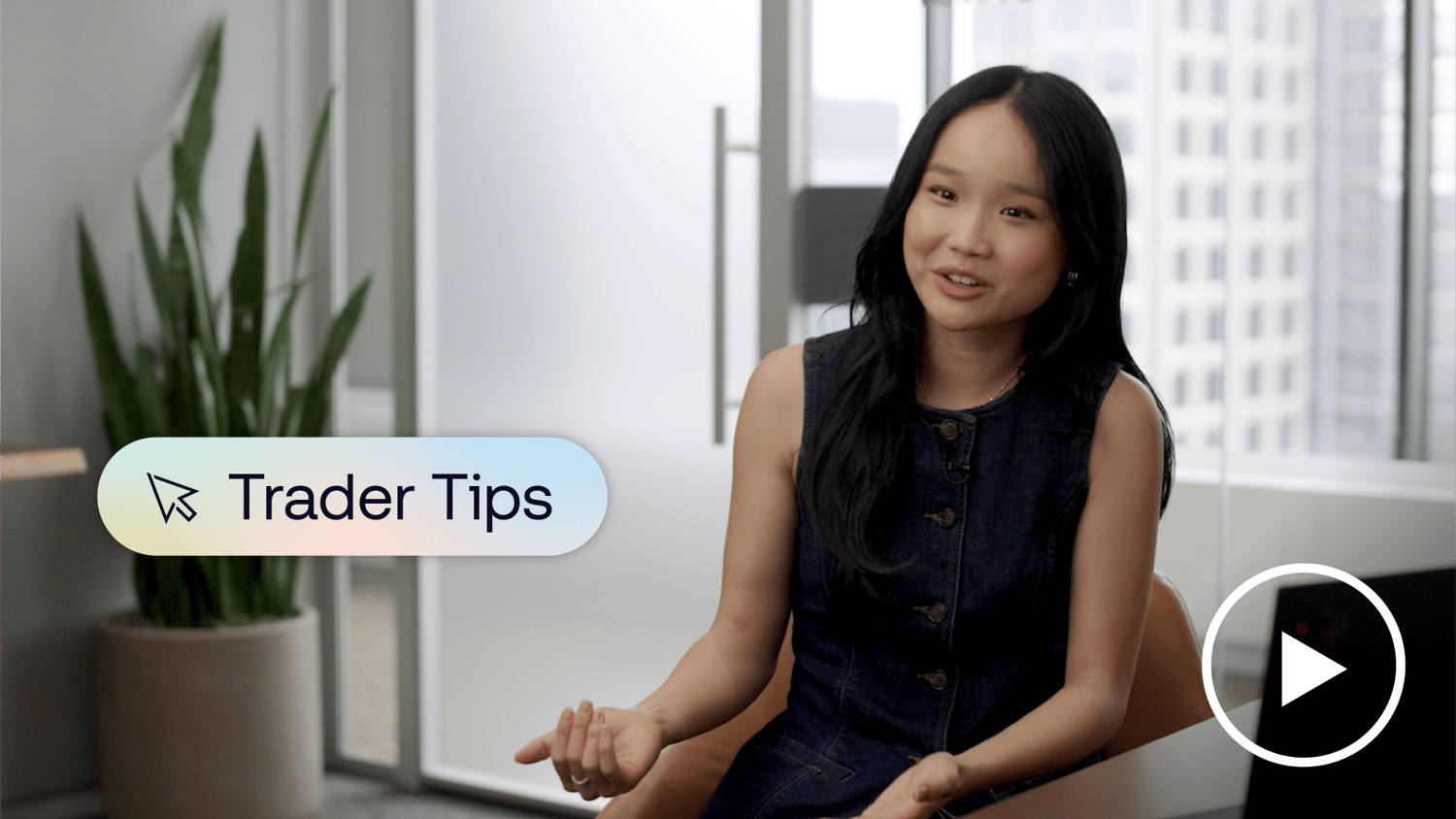 Candid image of a trader smiling at the camera while sitting at her desk with her laptop open. A banner on screen reads “Trader Tips."